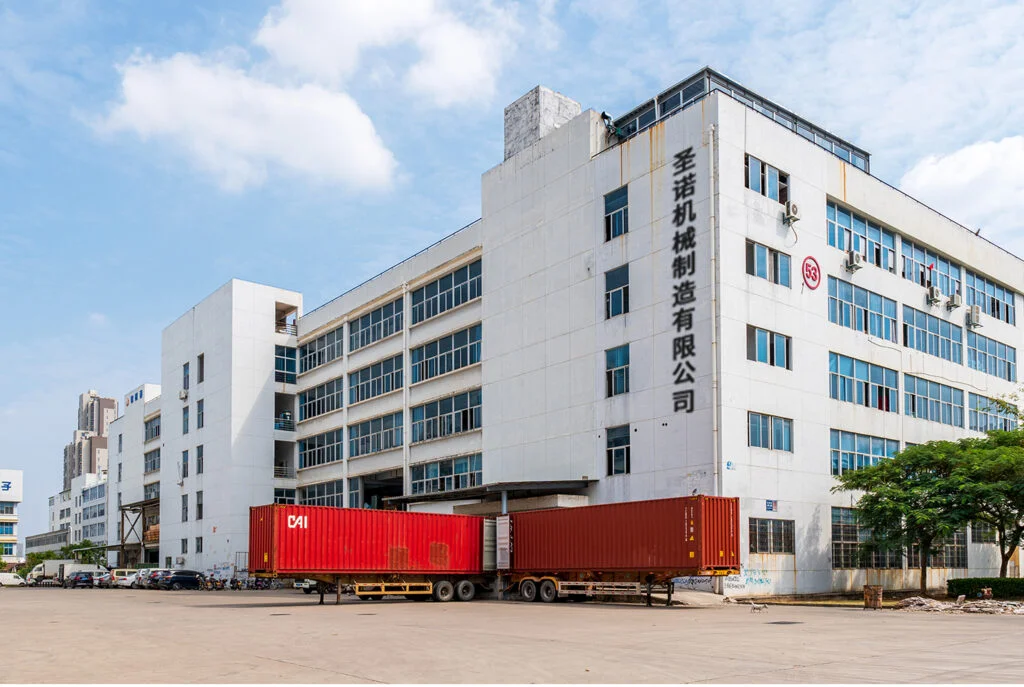Exterior view of SINOR machinery manufacturing factory building with loading container trucks